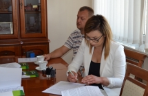 Kobieta w bialej bluzce podpisuje dokumenty
