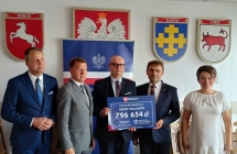 Czterech mezczyzn i kobieta trzymaja czek 