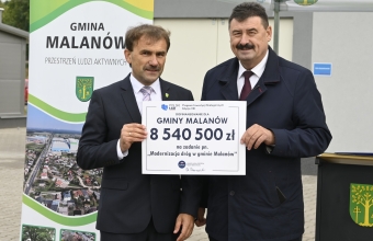 dwóch mężczyzn w garniturach trzyma kartkę 