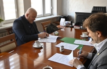 dwóch mężczyzn przy stole podpisują dokumenty