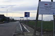 droga asfaltowa, z prawej strony biała tablica z napisami