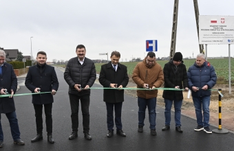 Grupa osób przecinająca wstęgę na drodze