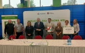 Grupa stojacych osob przy stole z bialym obrusem