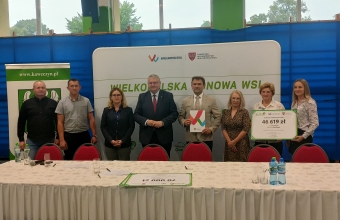 Grupa stojacych osob przy stole z bialym obrusem