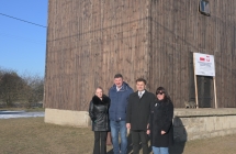 grupa stojacych osob w tle drewniany obiekt