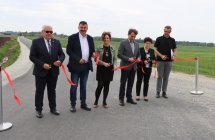 grupa osob przecina wstege na asfaltowej drodze