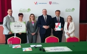 grupa osob stoi na tle scianki