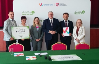 grupa osob stoi na tle scianki