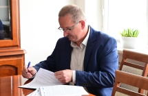 Meczyzna w garniturze podpisujacy dokumenty